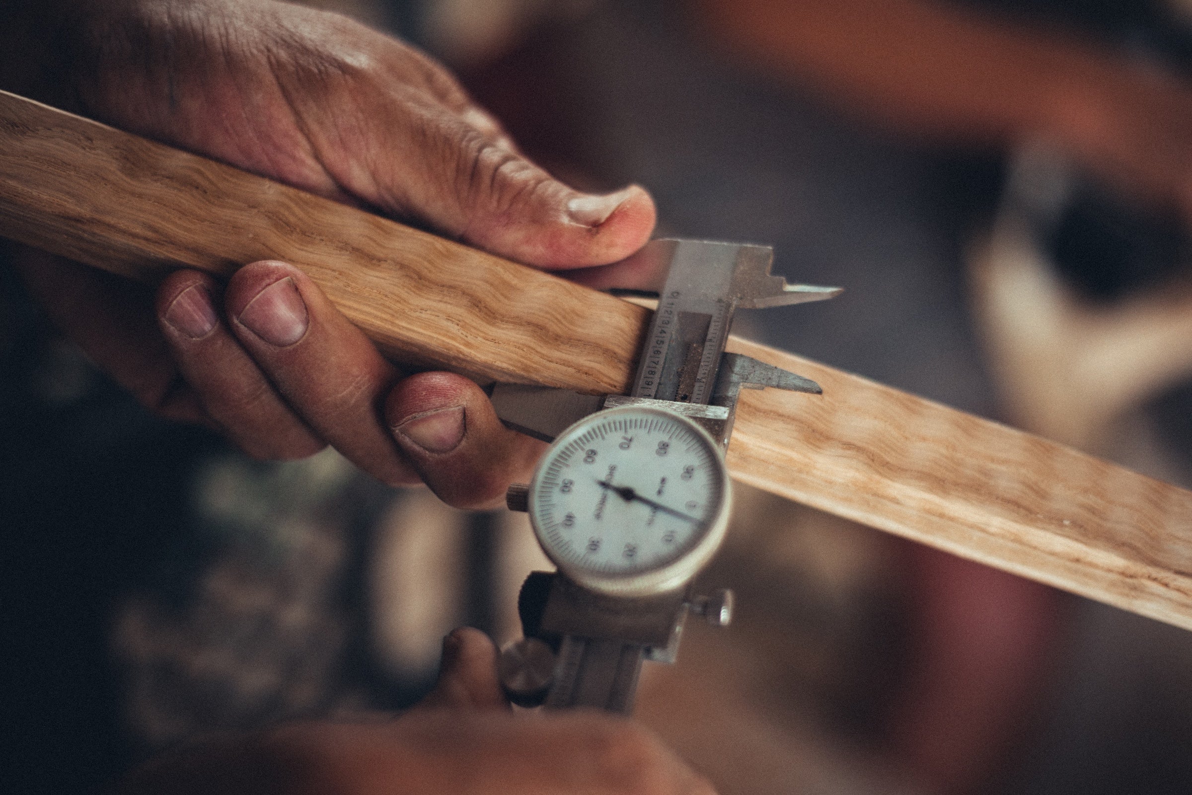 Person using a caliper to measure the thickness of a Classic Oak Kermit Chair leg piece. 