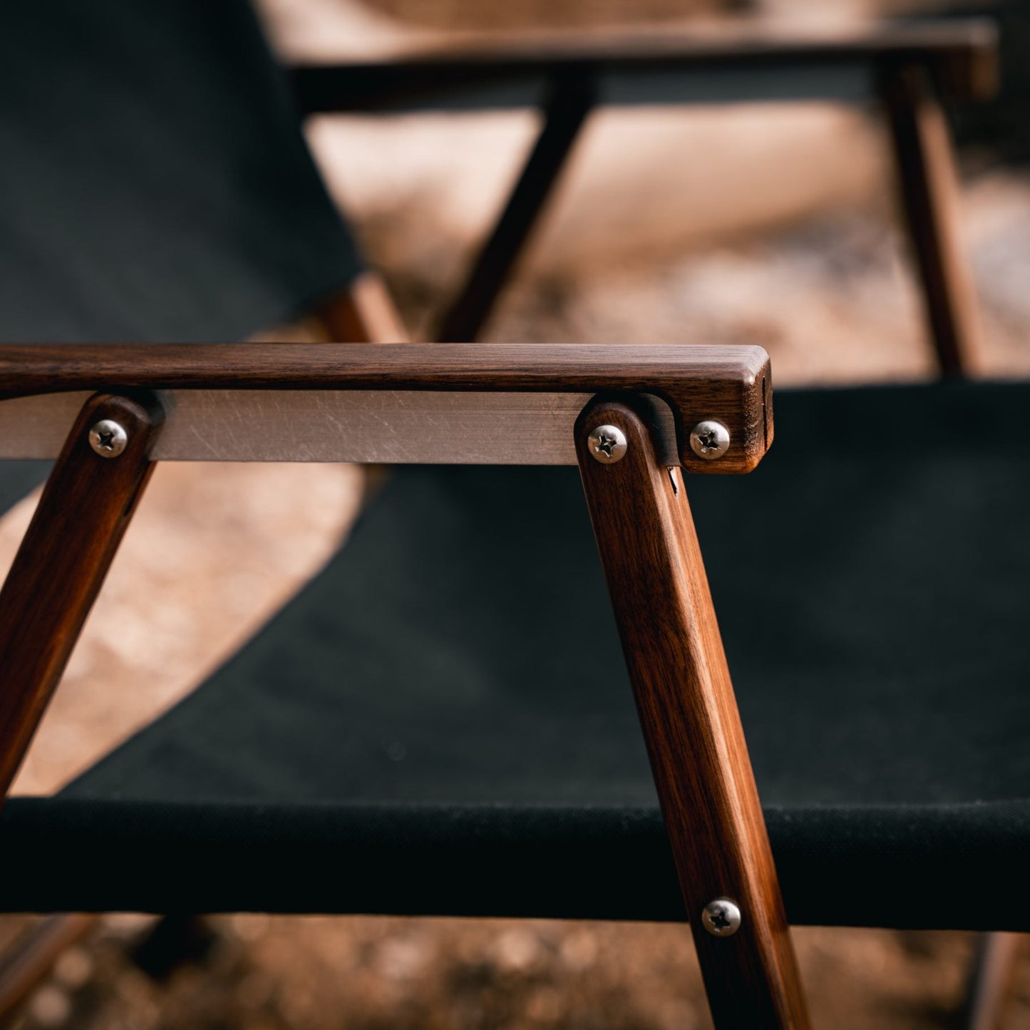 detail slow up shot of a walnut kermit chair arm rest with aluminium hardware screws and bolts luxury high-end camping glamping wooden furniture made by hand in America