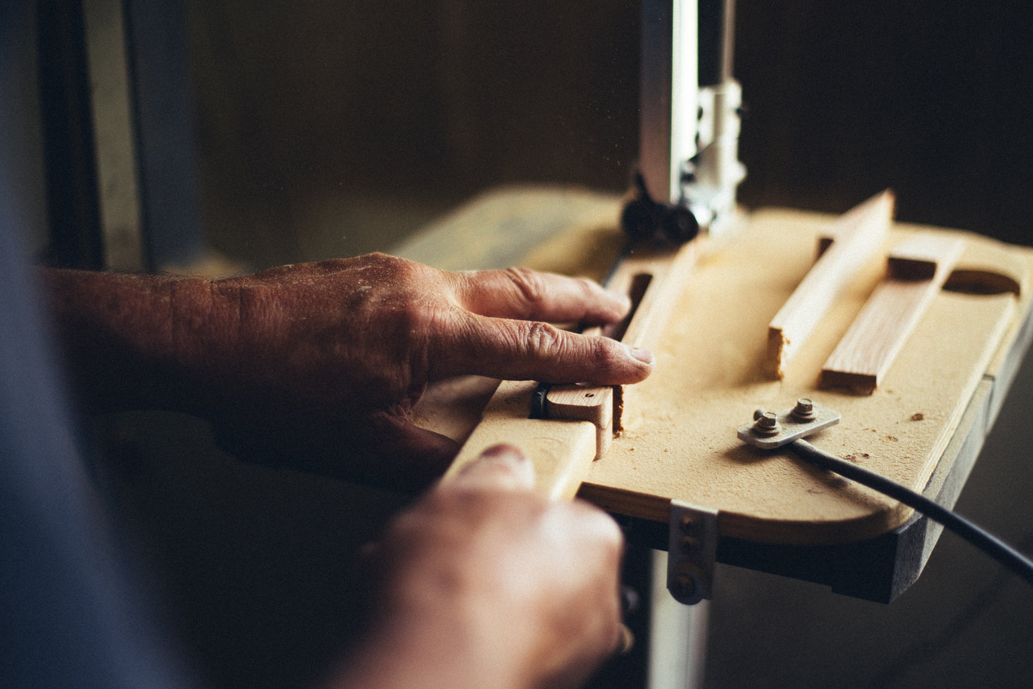 Man using woodworking maching to hand make kermit chair arm rest for glamping furniture